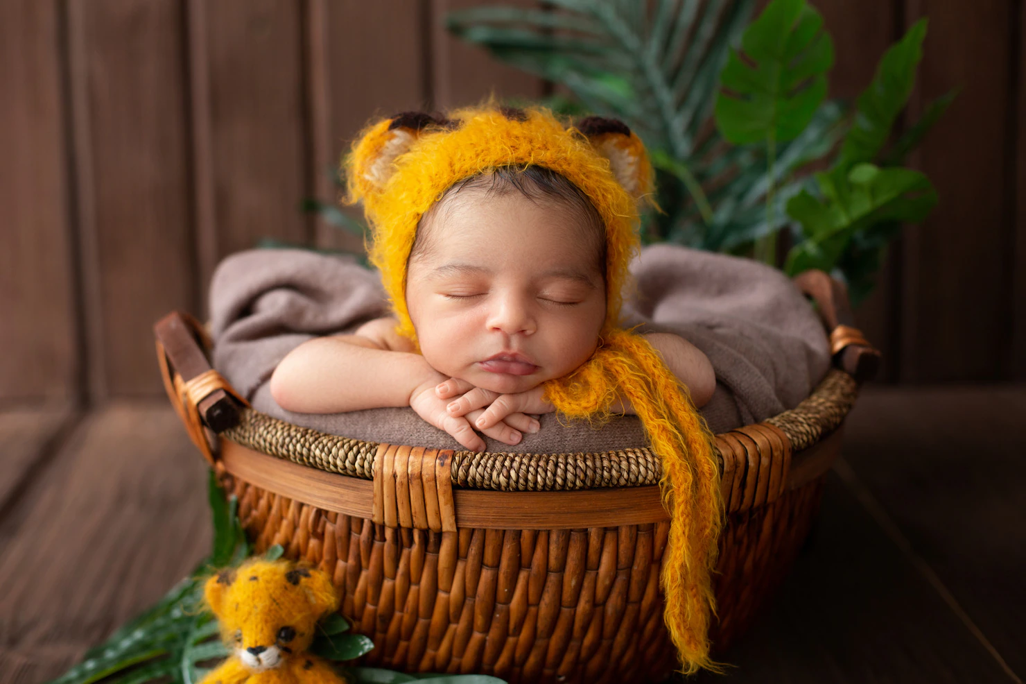 infant-sleeping-pretty-baby-boy-yellow-animal-shaped-hat-inside-brown-basket-along-with-green-leafs-wooden-room_179666-122