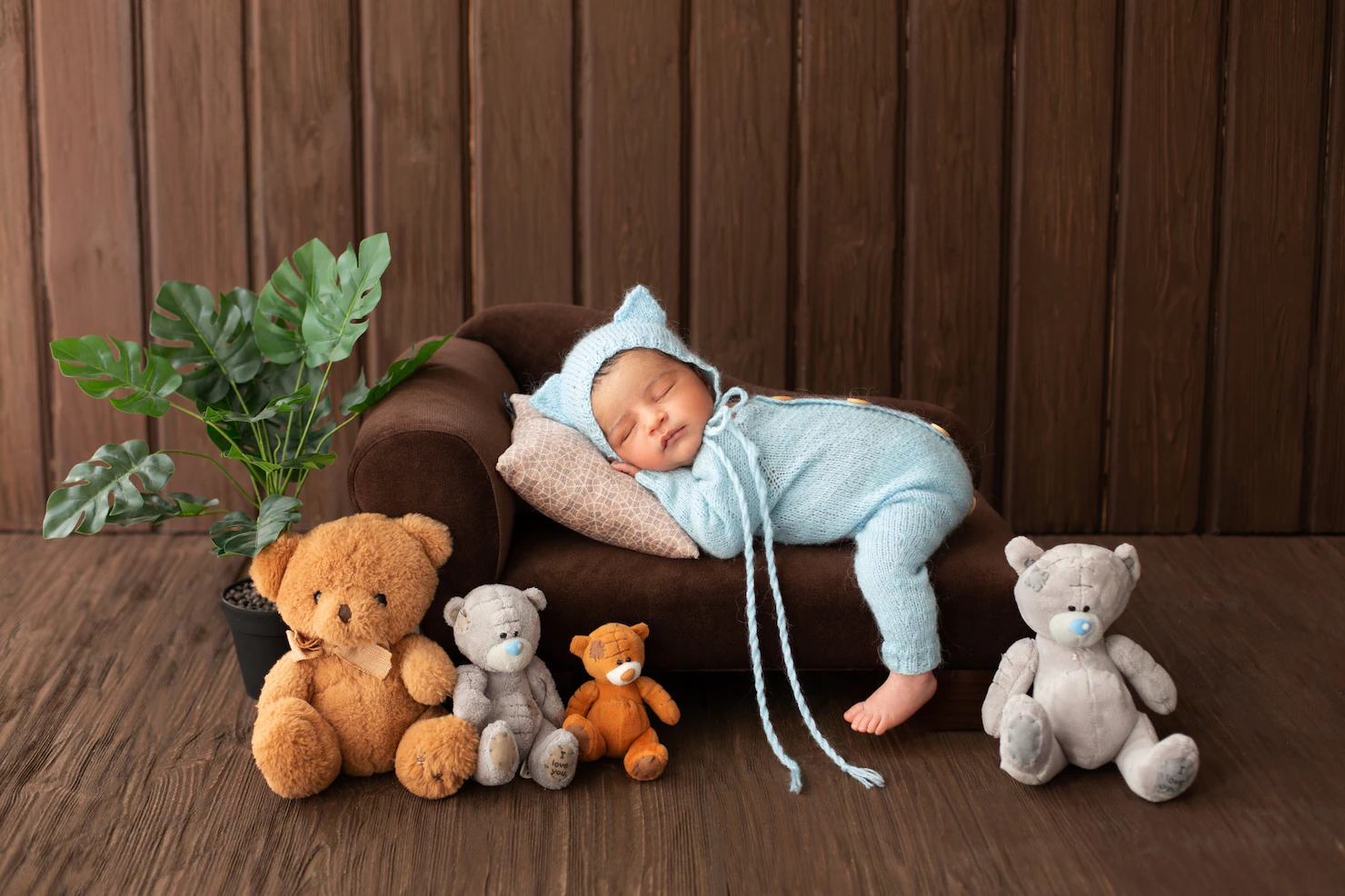 newborn-infant-little-likeable-pretty-baby-boy-sleeping-little-brown-sofa-blue-pijamas-surrounded-by-plant-toy-bears_179666-135